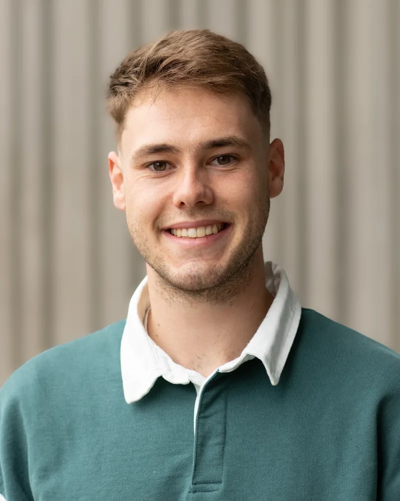 Elias Finke im grünen Polohemd, Studioaufnahme vor heller Lamellenwand