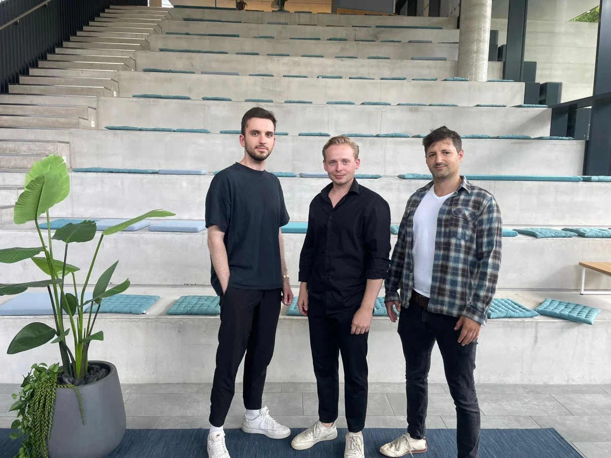 Konstantin Anklam, Ian Eberhardt und Giovanni Ronge stehen vor einer Sitztreppe in einem Bürogebäude